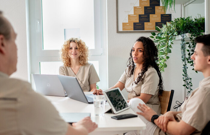 arehilliges-zahnarztpraxis-karriere-gruppensitzung Junges Team sitzt am Tisch bei einer Besprechung