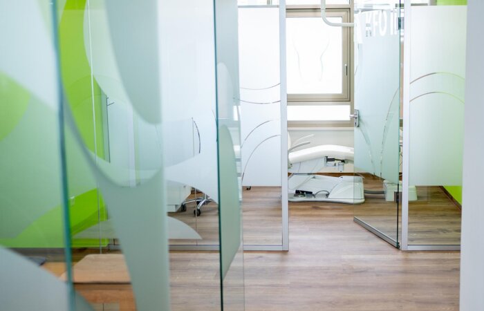 Praxisstuhl im Kieferorthopädie-Bereich durch Glastür und Wand mit Milchglasfolie