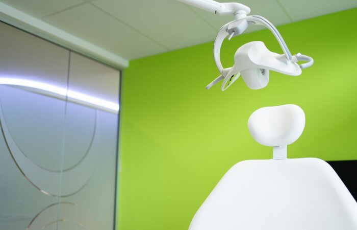 Weisser Zahnarztstuhl vor apfelgrüner Wand im Kieferorthopädie-Bereich
